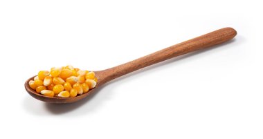 Kurutulmuş mısır taneleri ve beyaz arka plana yerleştirilmiş tahta kaşık. Patlamış mısır için mısır.