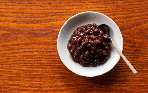 Boiled azuki beans in a dish placed on a wooden background. View from above.