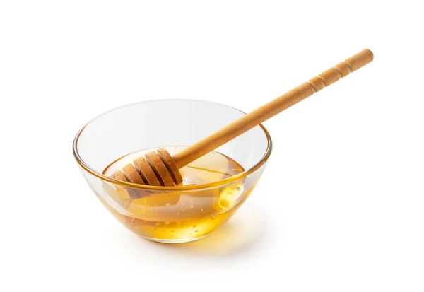 玻璃杯中的蜂蜜和白色底色的木制蜂蜜搅拌器 — 图库照片