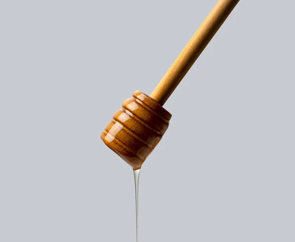 グレーの背景に蜂蜜と木の蜂蜜のディップ 蜂蜜のディップから滴り落ちる — ストック写真
