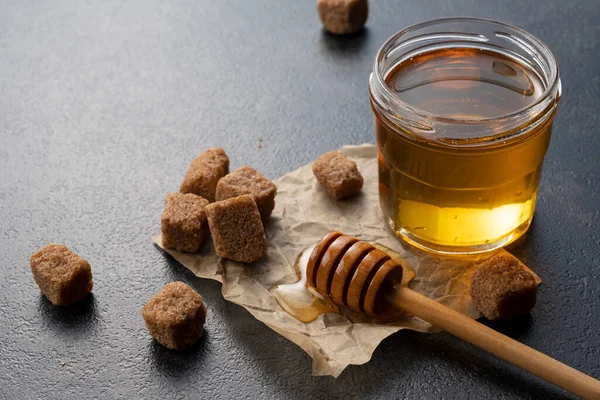 Brown sugar with honey and wooden honey dipper on stone background. Image of beauty.