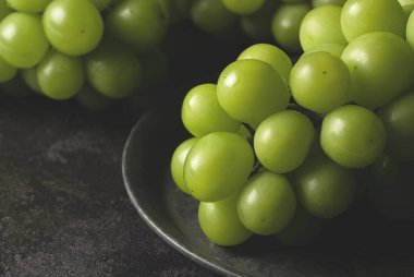 Muscat 'i siyah bir zemine demirden bir tabağa koy. Beyaz üzümler. Japon üzümleri.