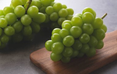 Shine Muscat siyah bir arka plana karşı bir kesme tahtasına yerleştirilmiş. Beyaz üzümler. Japon üzümleri.