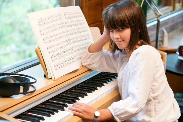 Porträt eines süßen kleinen Mädchens am Klavier. — Stockfoto