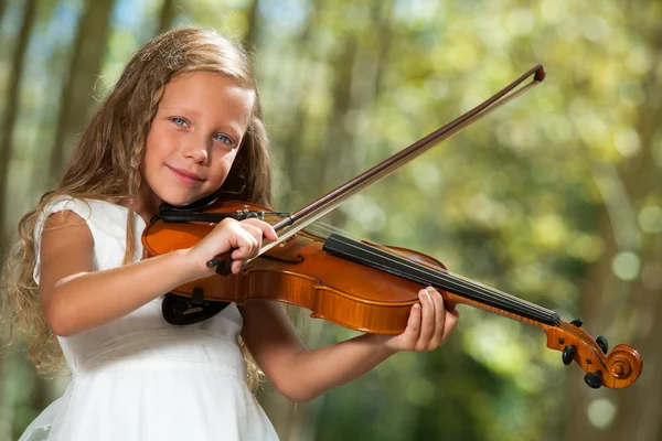 Милая девушка в белом играет на скрипке на открытом воздухе . — стоковое фото
