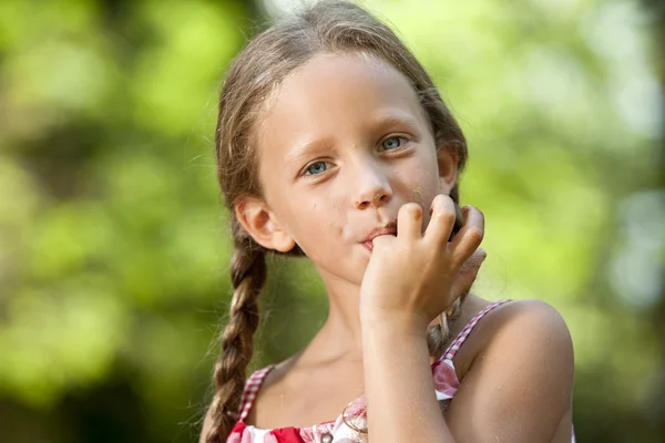 チョコレートの指を舐めるかわいい女の子. — ストック写真