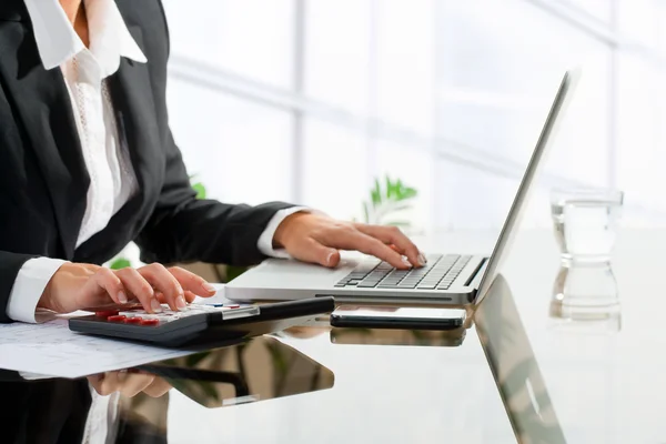 Female office worker doing accounting with calculator. Royalty Free Stock Photos