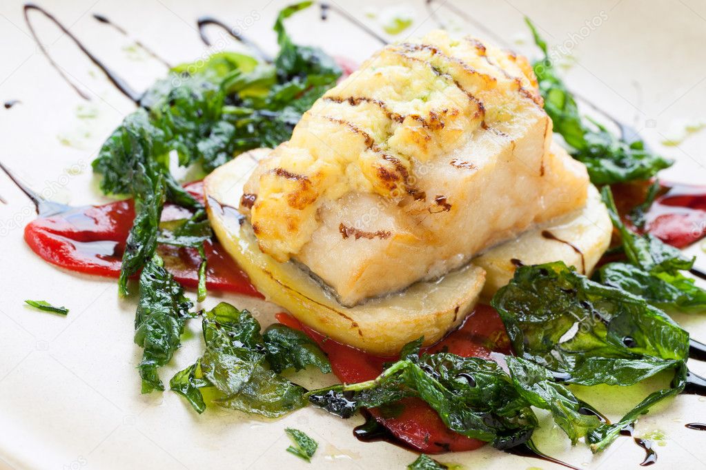 Grilled cod fish with spinach leaves.