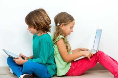 Two kids socializing with laptop and tablet.