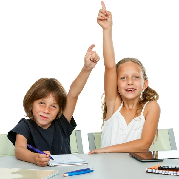 Two young students raising hands at desk. — Stock Photo, Image