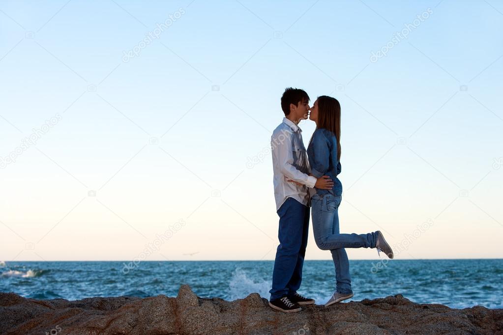 Romantic couple on rocks at seaside.