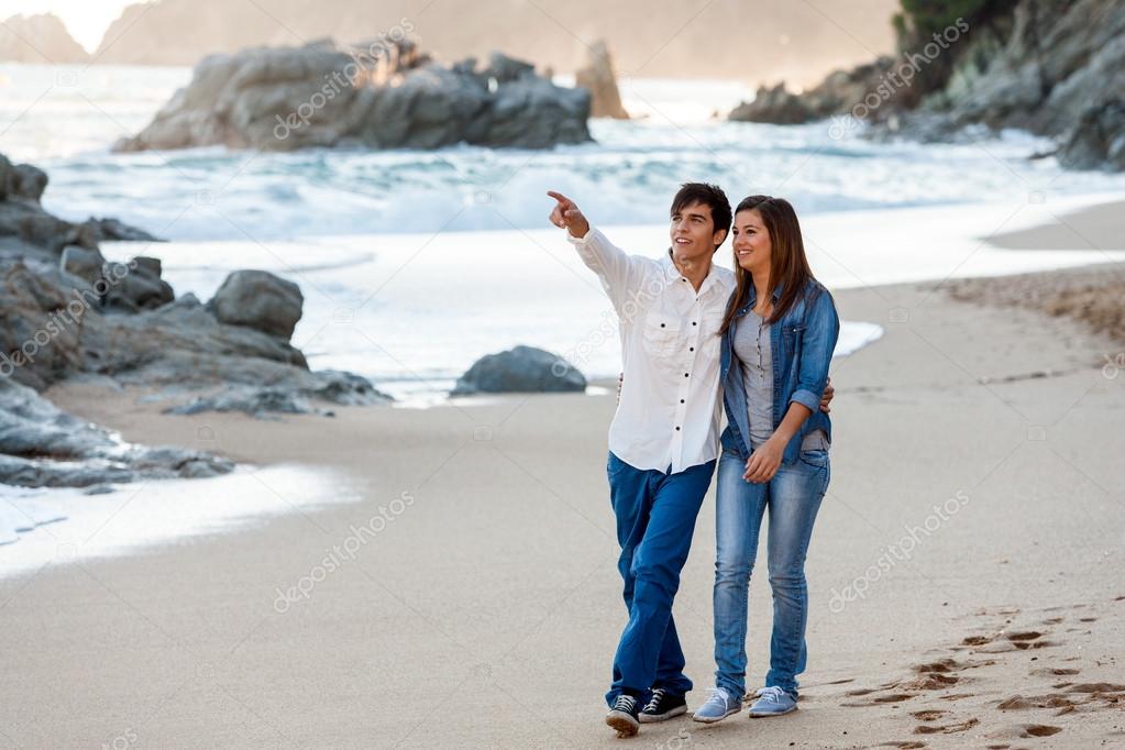 Young couple wandering along seashore.