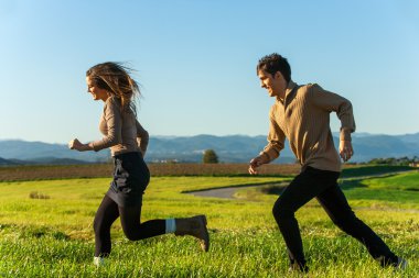 Happy couple having a race outdoors. clipart