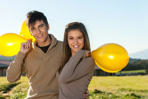 Cute tiener paar buitenshuis met ballonnen. — Stockfoto