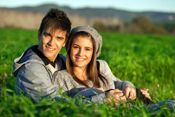 Retrato de casal adolescente sentado no campo de grama . — Fotografia de Stock