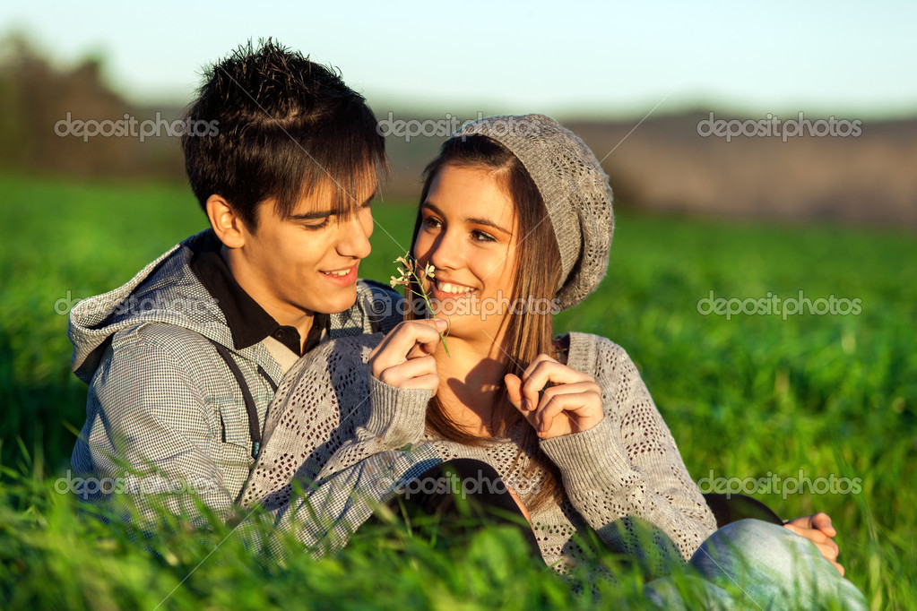 Girl showing flower to boyfriend outdoors.