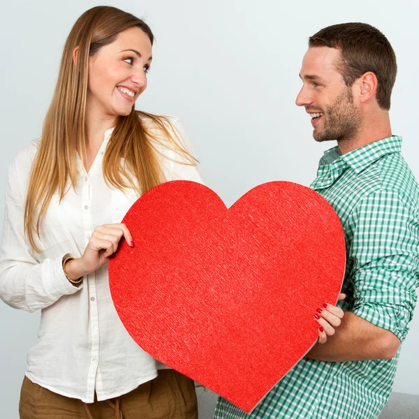 Bonito casal segurando grande sinal de coração vermelho . — Fotografia de Stock