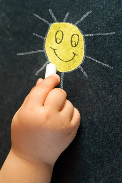 Mão infantil desenhando um sol sorridente . — Fotografia de Stock