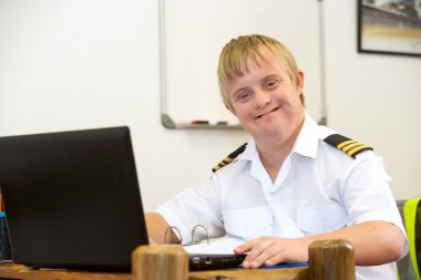 Portrait of young pilot with down syndrome at desk. clipart