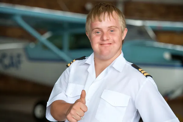 Jovem piloto com síndrome de down mostrando polegares para cima . — Fotografia de Stock