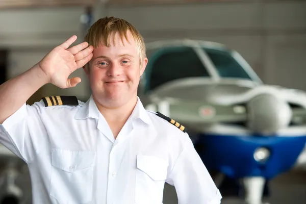 Portret młodego pilota z zespołem Downa w hangarze. — Zdjęcie stockowe