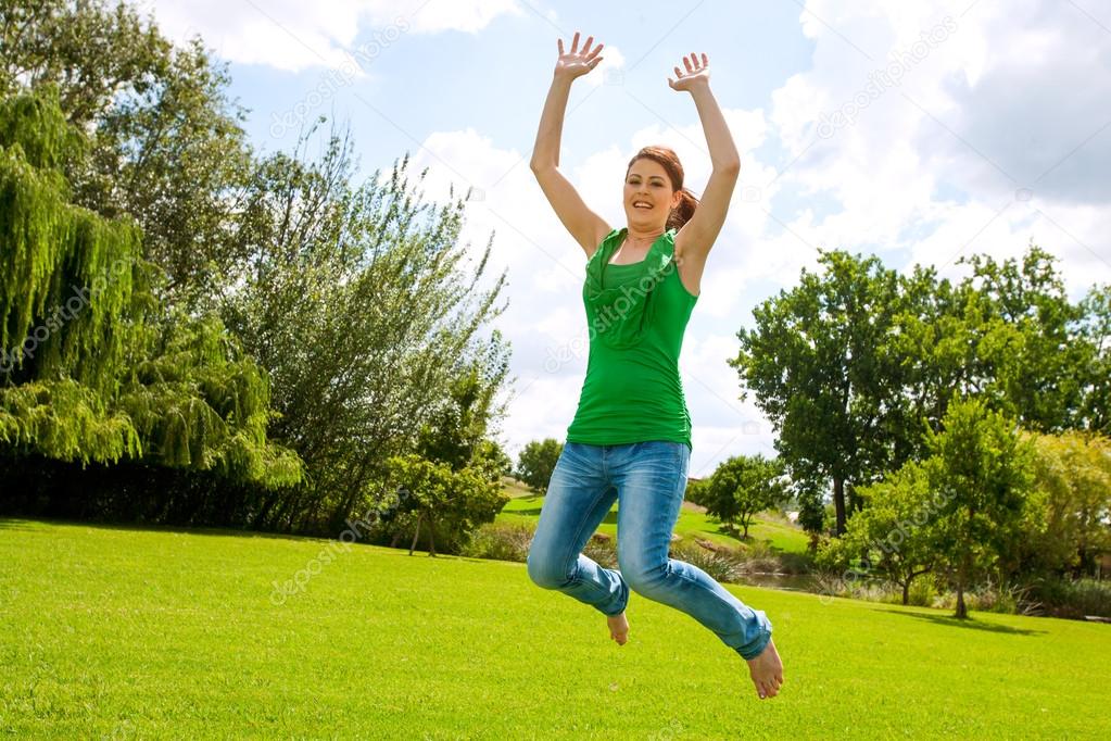 Young girl jumping high in green park.