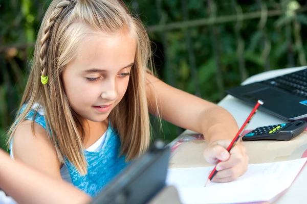 Menina bonito fazendo trabalhos escolares ao ar livre . — Fotografia de Stock