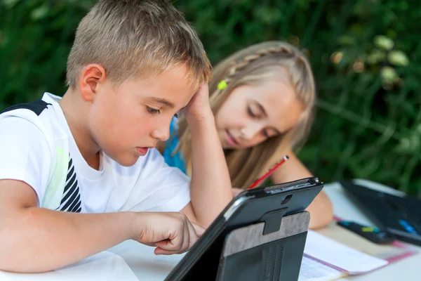 Kinderen doen van huiswerk ourdoors. — Stockfoto