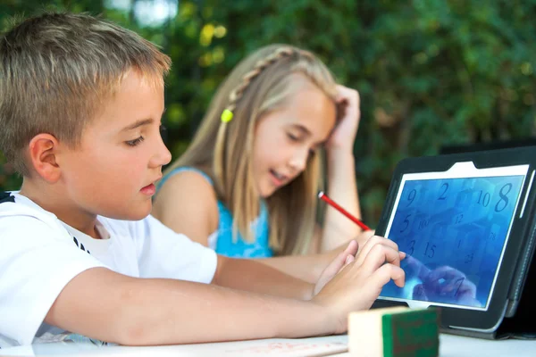 Lindo chico resolviendo juego de matemáticas en la tableta . — Foto de Stock