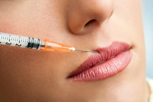 Jeringa de macro botox en labios femeninos . — Foto de Stock