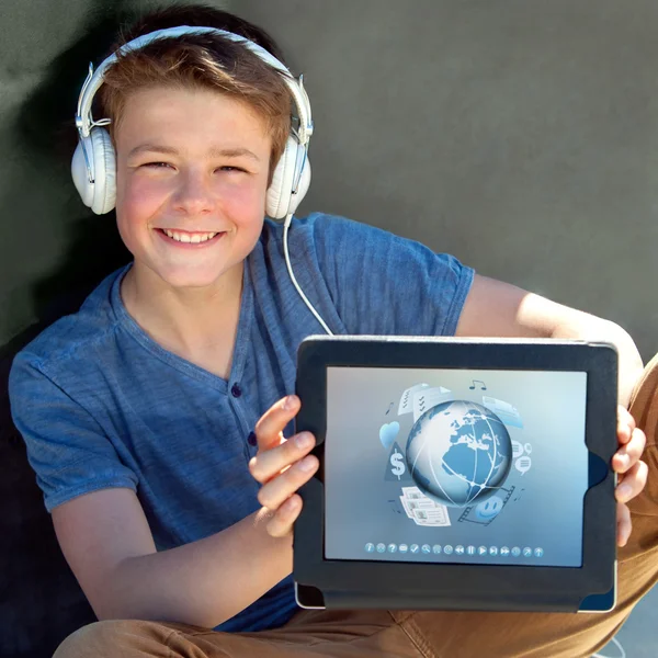Симпатичный мальчик показывает планшет с мультимедийными символами . — стоковое фото