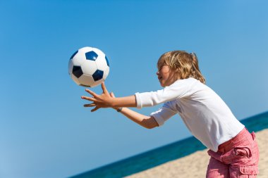 Boy playing with ball on beach. clipart
