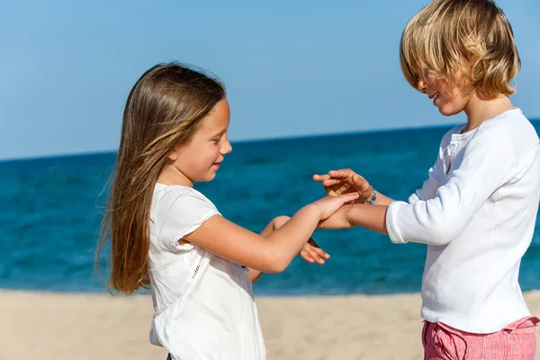 沙滩上的男孩和女孩玩手游戏. — 图库照片