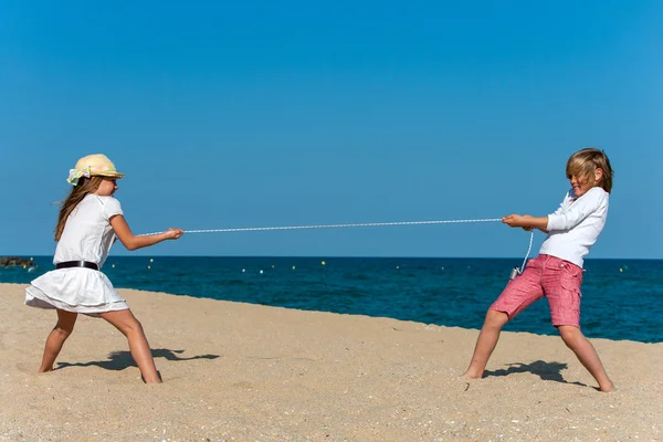 Barn med ett rep krig på stranden. — Stockfoto