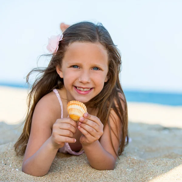 Doce menina segurando concha na praia . — Fotografia de Stock