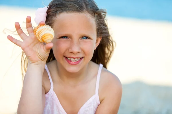 Menina bonito mostrando concha na praia . — Fotografia de Stock