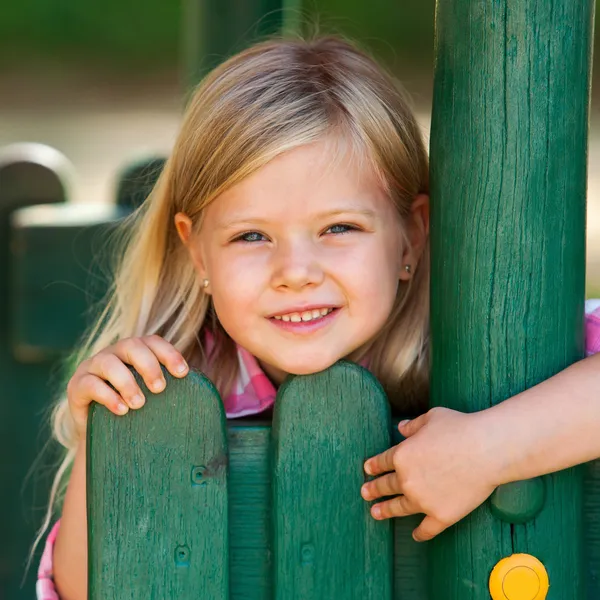 Leuk meisje vasthouden aan houten hek. — Stockfoto