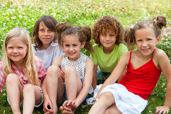 Kinder sitzen zusammen im Blumenfeld. — Stockfoto