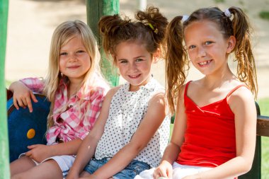 Three little girl friends in park. clipart