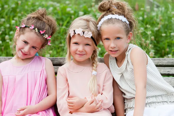 Drie schattig meisje vrienden samen zitten op houten bank. — Stockfoto