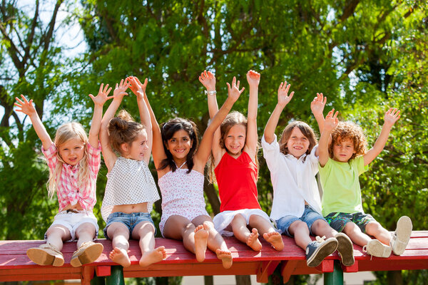 Happy kids raising hands outdoors.