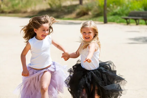 Zwei Mädchen laufen mit fantasievollen Kleidern im Park. — Stockfoto