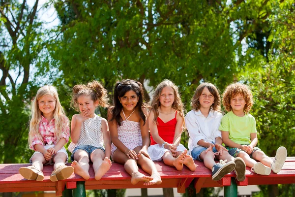 Sechs Kinder sitzen zusammen auf Dach im Park. — Stockfoto