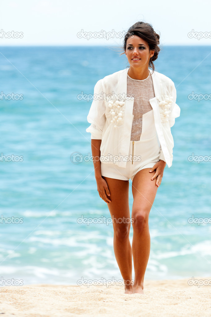 Elegant brunette in white on beach.