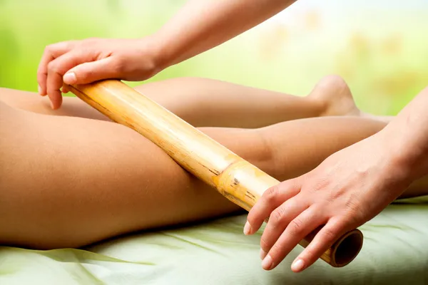 Mãos massageando pernas femininas com bambu . — Fotografia de Stock