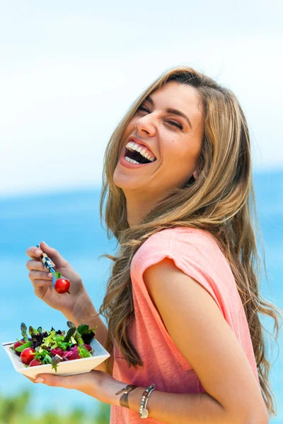 Сміється дівчина їсть свіжий салат на відкритому повітрі . — стокове фото
