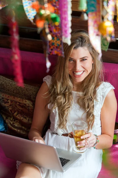 Atractiva rubia tomando un descanso para tomar el té con el portátil . — Foto de Stock