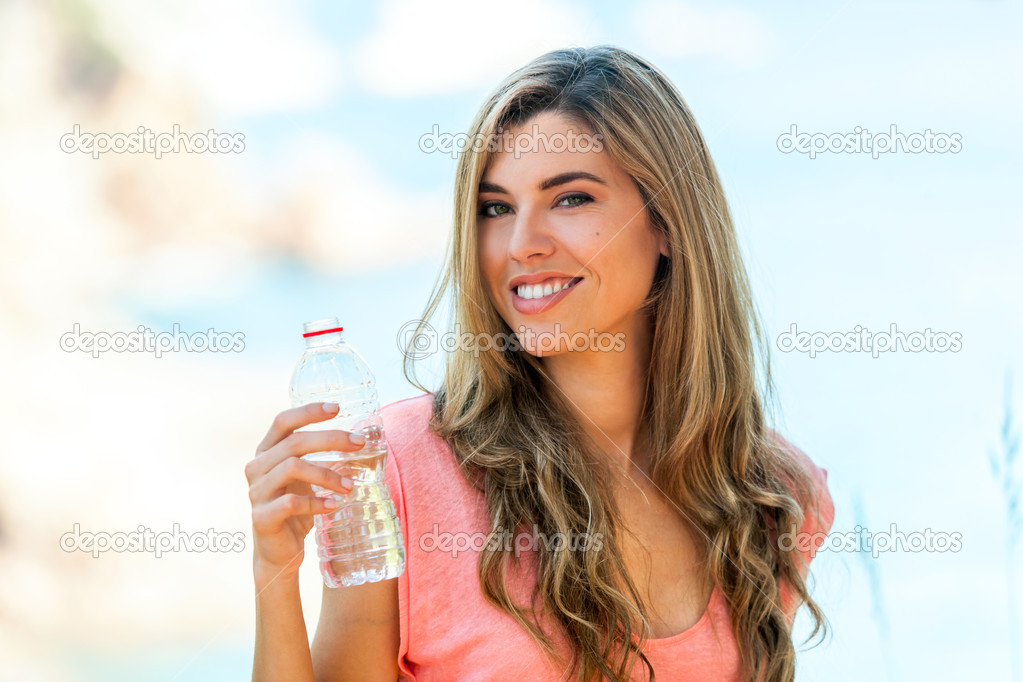 Attractive woman holding water bottle outdoors.