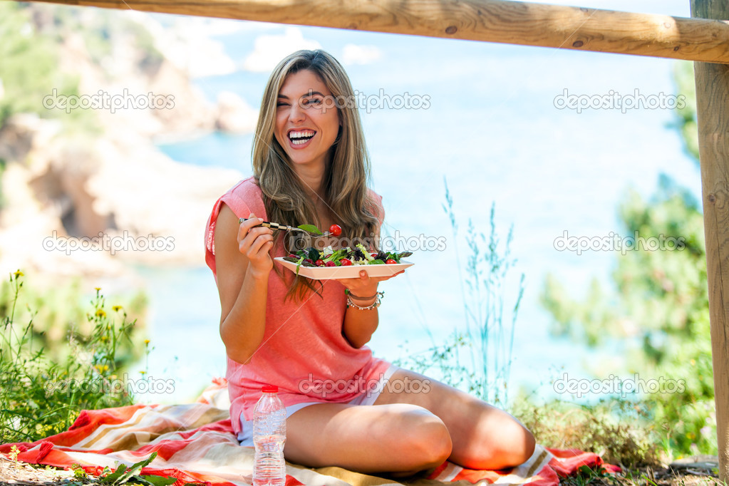 Attractive woman having healthy picnic outdoors.