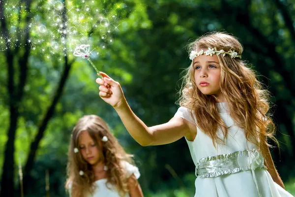 Mädchen schwingt Zauberstab im Wald. — Stockfoto